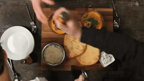 two people are sitting at a table with plates and bowls of food including a bowl of curry