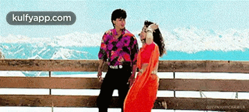 a man and a woman are standing next to each other on a railing .