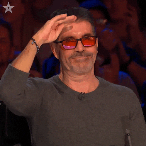 a man wearing sunglasses and a gray shirt with a star on the bottom