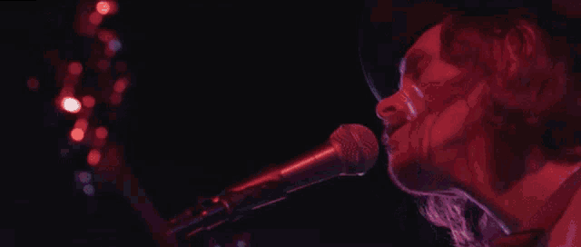 a close up of a person singing into a microphone in a dark room .