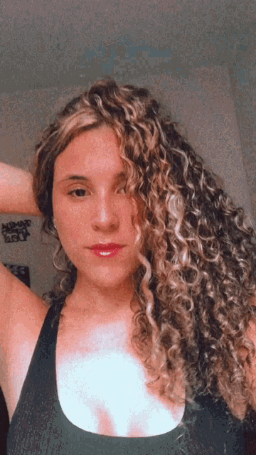 a woman with curly hair is taking a selfie in front of a sign that says nomad