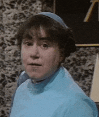 a woman wearing a blue sweater and a blue headband is looking at the camera .