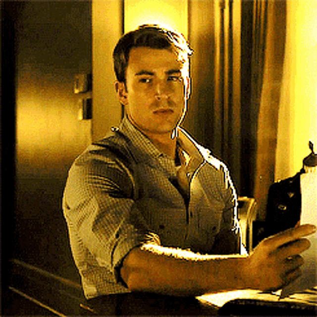 a man in a plaid shirt is sitting at a table looking at something