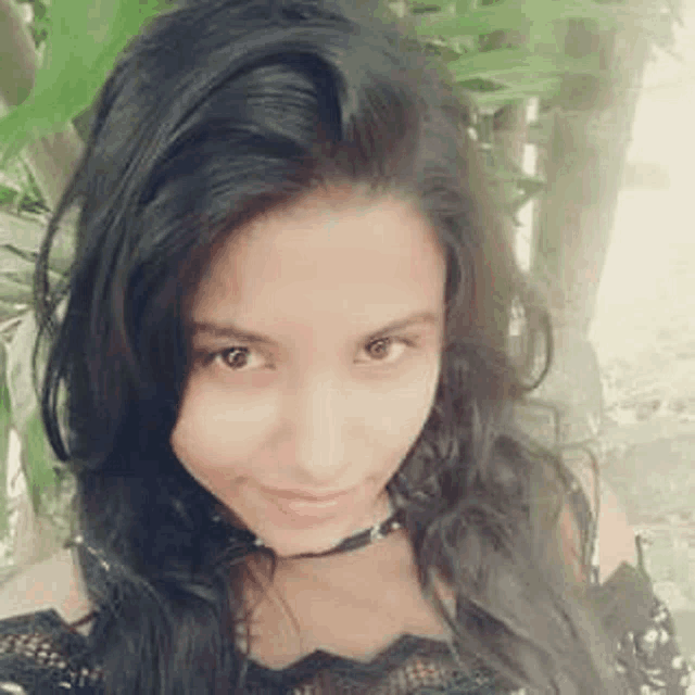 a close up of a woman 's face with long black hair and a choker .