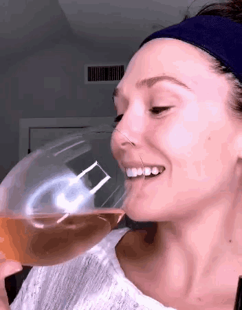 a woman is drinking from a glass with the letter a on it