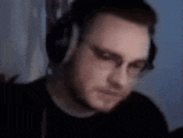 a man wearing headphones and glasses is sitting in front of a computer .