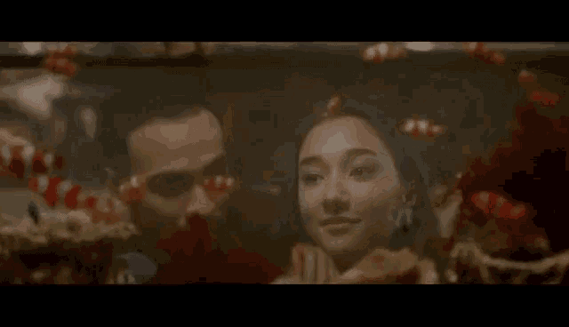 a man and woman are looking at fish in a tank .