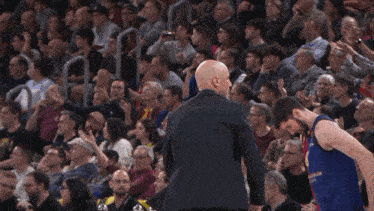 a man in a suit talks to a basketball player in a barcelona jersey