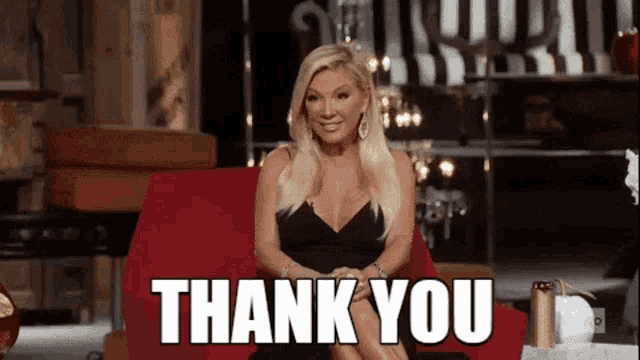 a woman in a black dress is sitting in a red chair with the words `` thank you '' above her .