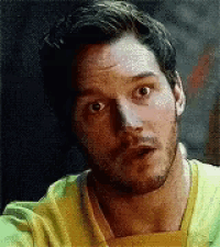 a man with a beard is wearing a yellow shirt and making a funny face .