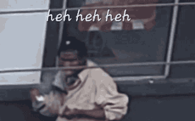 a man smoking a cigarette in front of a window with the words heh heh heh written on the bottom