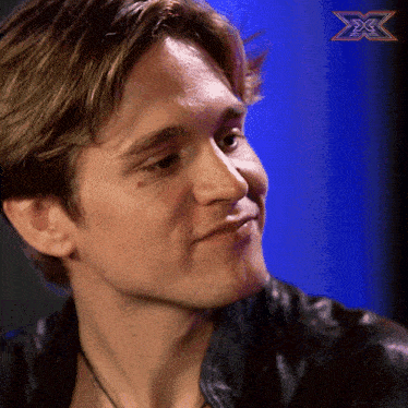 a close up of a man 's face with a x on the bottom right