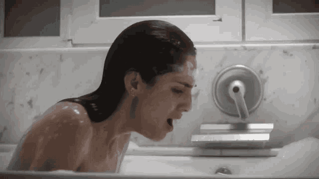 a woman is taking a bath in a tub with her mouth open