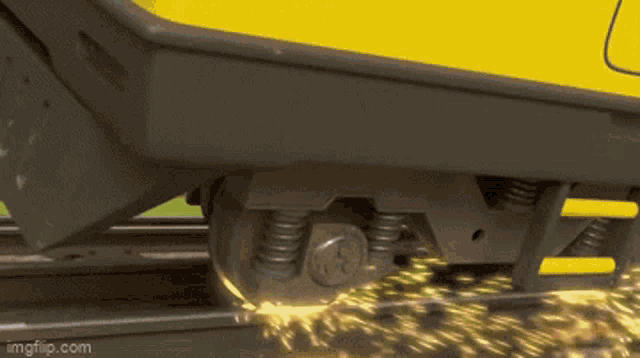 a yellow train is going down the tracks and sparks are coming out of it 's wheels