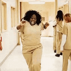 a woman in a prison uniform is dancing in a hallway