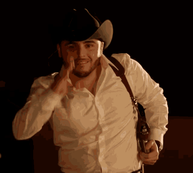 a man wearing a cowboy hat holds a gun