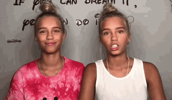 two girls are standing next to each other in front of a wall that says if you can dream it