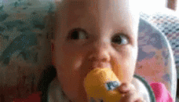 a baby in a high chair is eating a yellow ice cream cone