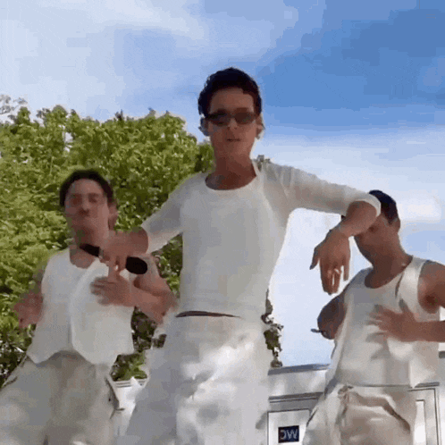 a man in a white shirt is dancing with two other men