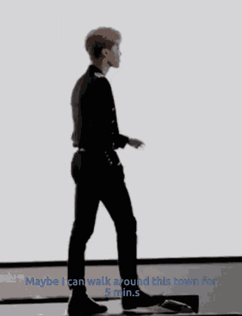 a man in a black suit is walking with the words maybe i can walk around this town for 5 minutes underneath him