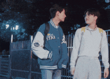 two young men standing next to each other one wearing a blue jacket with the word star on it