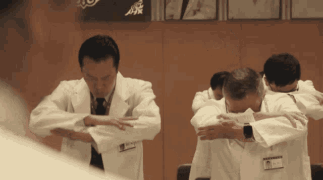 a group of doctors are stretching their arms in front of a sign that says ' a ' on it