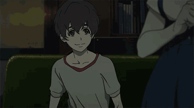a boy in a grey shirt with a red collar is sitting on a couch