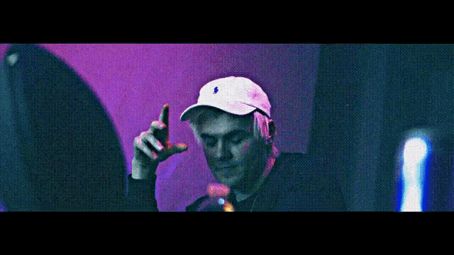 a man wearing a white polo hat is making a hand gesture