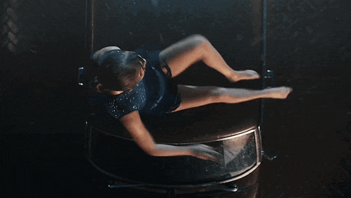 a woman in a blue leotard is laying on her back with her arms outstretched