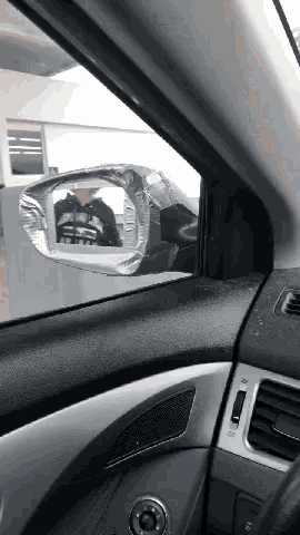 a man in a skeleton shirt is reflected in the side view mirror of a car