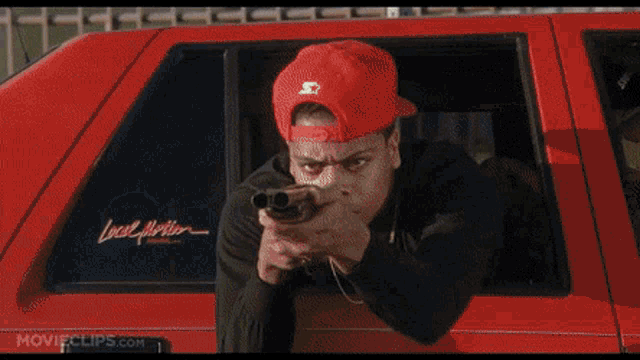 a man in an orange hat is smoking a cigarette in a car with movieclips.com on the bottom right