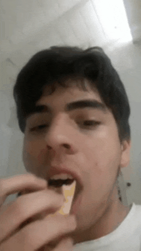 a young man is eating a piece of food with his hands .