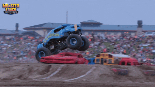 a monster truck is jumping over a red car at a monster truck show