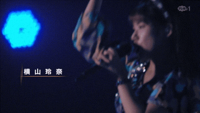 a woman is singing into a microphone in front of a blue light
