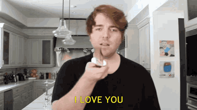 a man in a black shirt says i love you in a kitchen