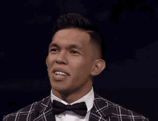 a man wearing a plaid suit and bow tie is smiling