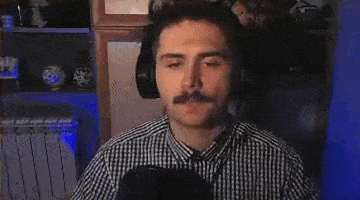a man wearing headphones and a plaid shirt is making a peace sign with his hands .