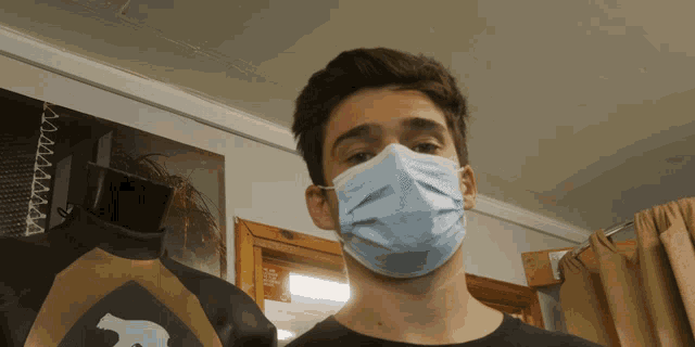 a man wearing a face mask is standing in front of a sign that says " no smoking "