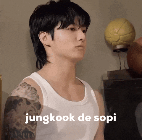 a young man with a tattoo on his arm is wearing a white tank top with the words jungkook de sopi on it