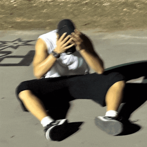 a man wearing a white tank top and black shorts is covering his face with his hands