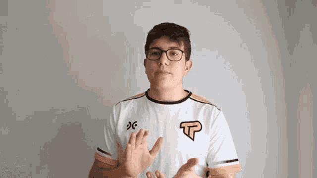 a man wearing glasses and a white shirt is clapping his hands .