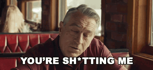 a man is sitting in a diner with the words you 're sh * tting me behind him