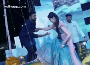 a woman in a blue dress is dancing with a man in a blue shirt .