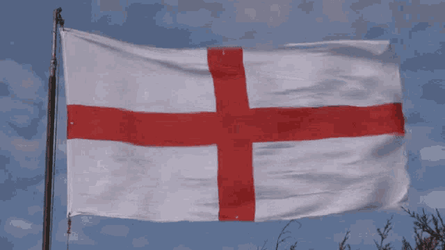 a white flag with a red cross on it is waving in the wind