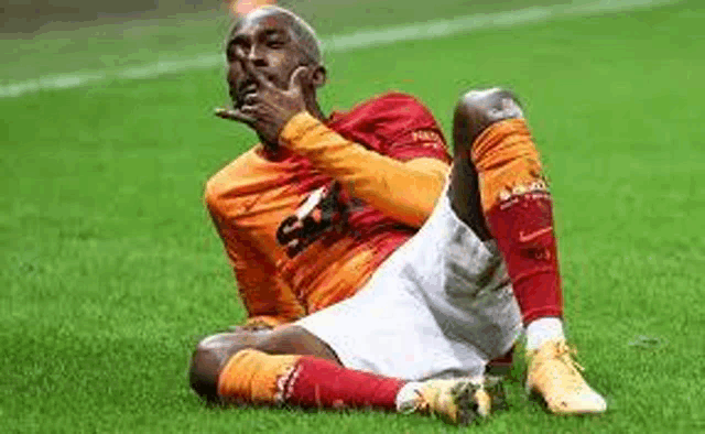 a soccer player is sitting on the grass with his hands on his face .