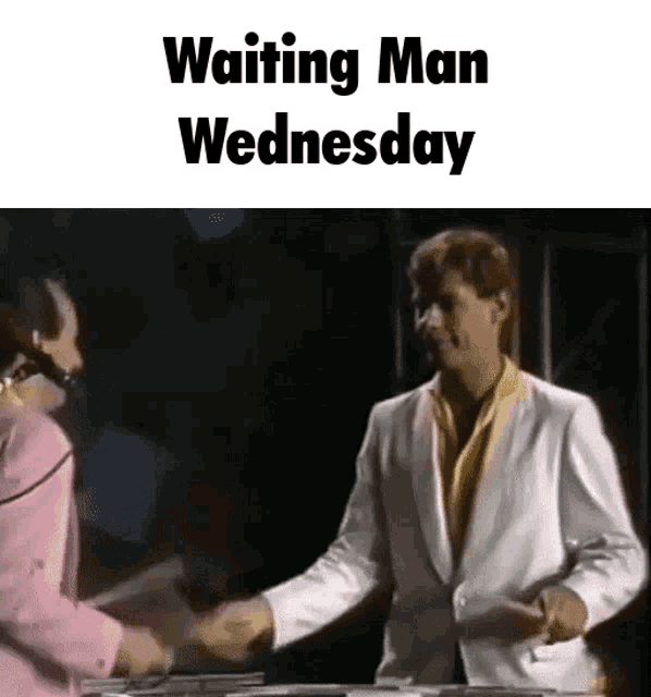 a man in a white suit shakes hands with a woman in a pink shirt while waiting for wednesday .