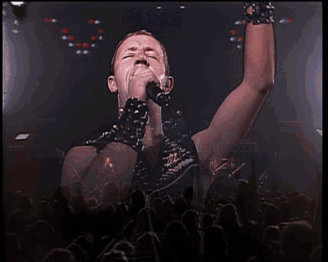 a man is singing into a microphone in front of a crowd of people