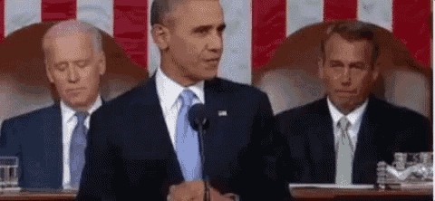 barack obama is giving a speech in front of a microphone while sitting in front of two other men .