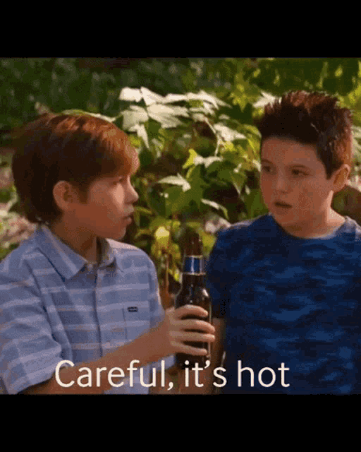 two young boys standing next to each other with one holding a bottle of beer and the words careful it 's hot above them