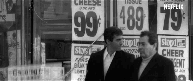 two men standing in front of a sign that says cheese